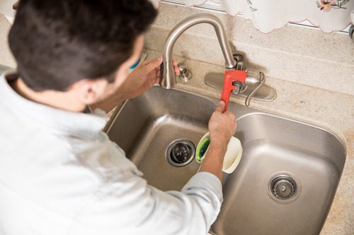 male-plumber-using-wrench-tighten-water-faucet-kitchen-seen-up-close